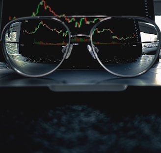 a pair of glasses sitting on top of a laptop computer